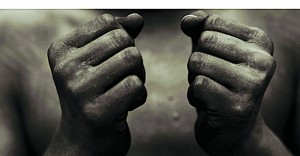 Black person wearing black paint, holding fist in front of chest in sign of freedom and power. Photo courtesy of Black Press USA